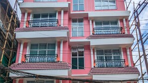 Een meerhoog, roze gebouw met balkons, een bord waarop staat 