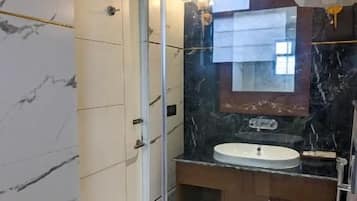 Une salle de bain moderne avec une douche à parois de verre, un sol carrelé en marbre, des toilettes blanches et un meuble-lavabo avec un miroir.