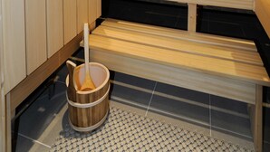 A sauna with wooden benches and a wooden bucket with a ladle. - Hotel Valerie (Saalbach-Hinterglemm)