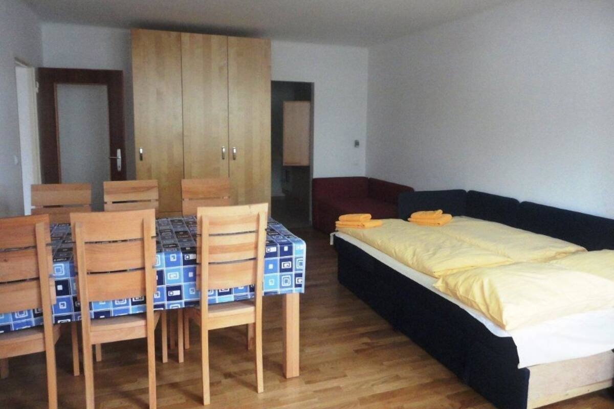 Una habitación con una cama, un armario de madera, una mesa de comedor con sillas y una silla roja.