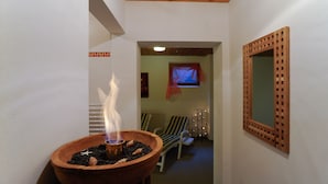 A hallway with a wooden bowl stove, a window with a red curtain, and a wooden lattice wall decoration. - Hotel Valerie (Saalbach-Hinterglemm)