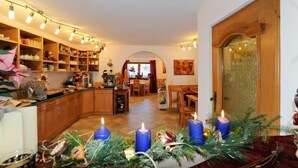 A cozy kitchen with wooden cabinets, a dining area with a table and chairs, and a doorway leading to another room. - Hotel Valerie (Saalbach-Hinterglemm)