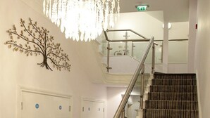 A staircase with a striped carpet, a metal handrail, and a wall-mounted tree decoration. - Austen's Luxury Apartments (Torquay)
