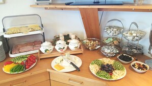 Une table de buffet proposant une variété d’aliments, notamment des fruits, des fromages et des pâtisseries.