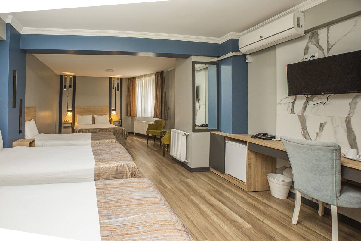 Ett hotellrum med två sängar, ett skrivbord, en stol, en tv och en spegel.