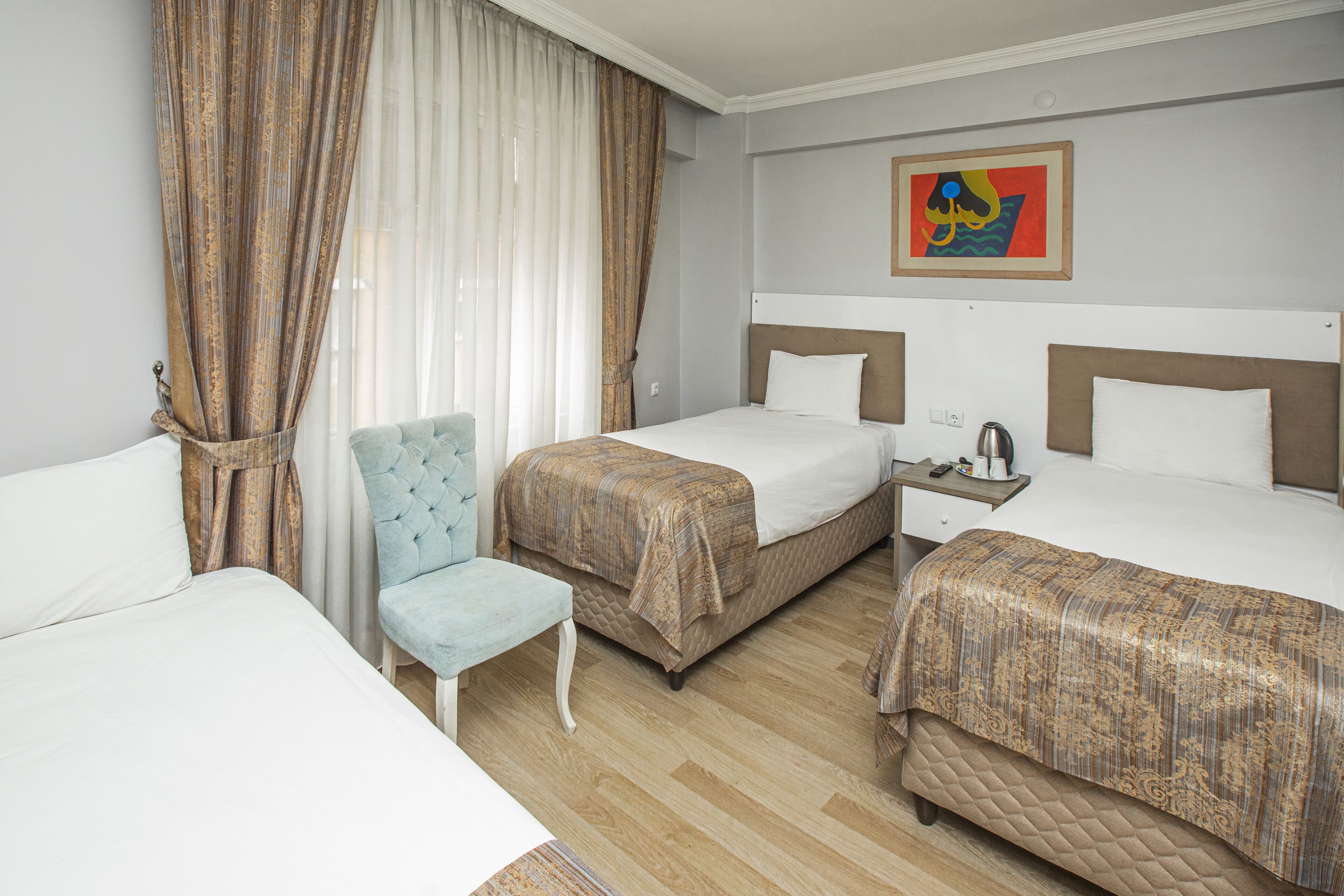 A hotel room with two beds, a chair, a nightstand, and a painting on the wall.