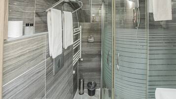 Ein modernes Badezimmer mit einer gläsernen Dusche, einer weißen Toilette und einem Handtuchhalter.