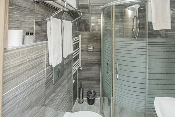 A modern bathroom with a glass-enclosed shower, a white toilet, and a towel rack.