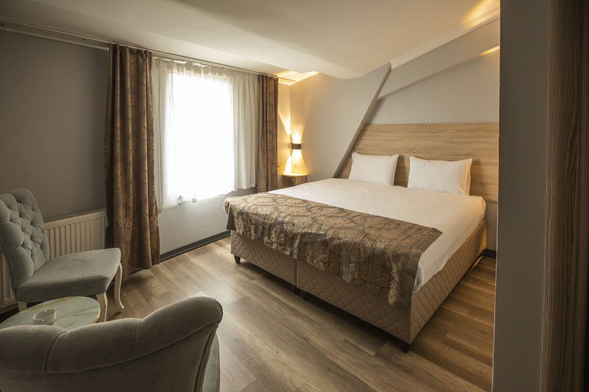 Ett hotellrum med en stor säng, en sittgrupp med en fåtölj och en lampa.