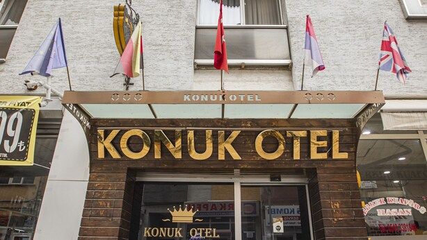Het uiterlijk van Konukotel, met een ruime ingang, plantenpotten en vlaggen.