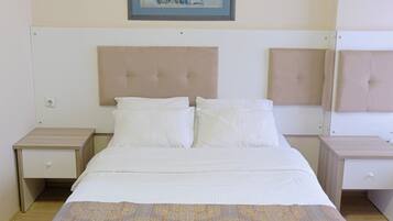 A hotel room with a bed, two nightstands, a headboard, and a framed artwork on the wall.
