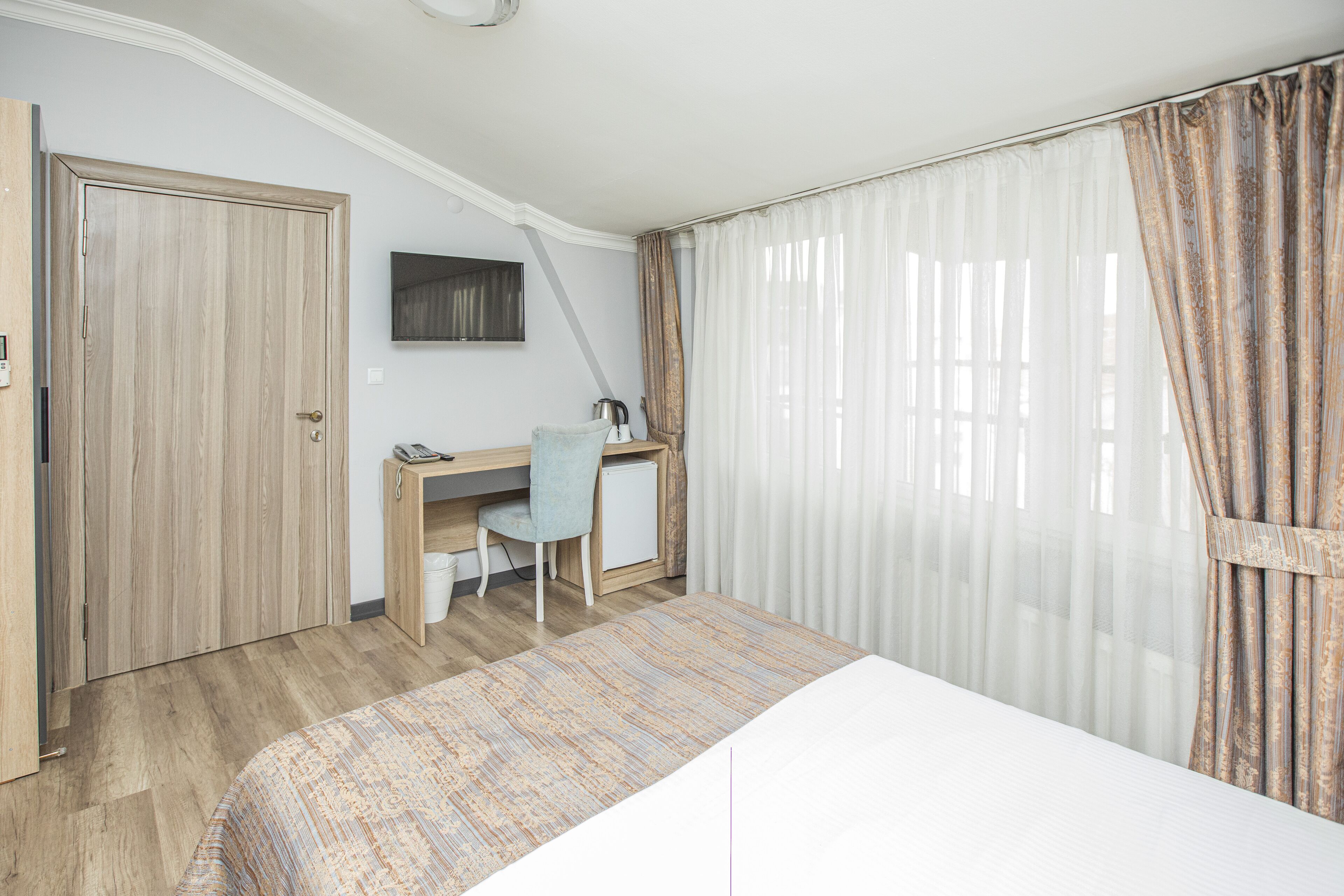 A bedroom with a bed, a desk, a chair, and a wardrobe.