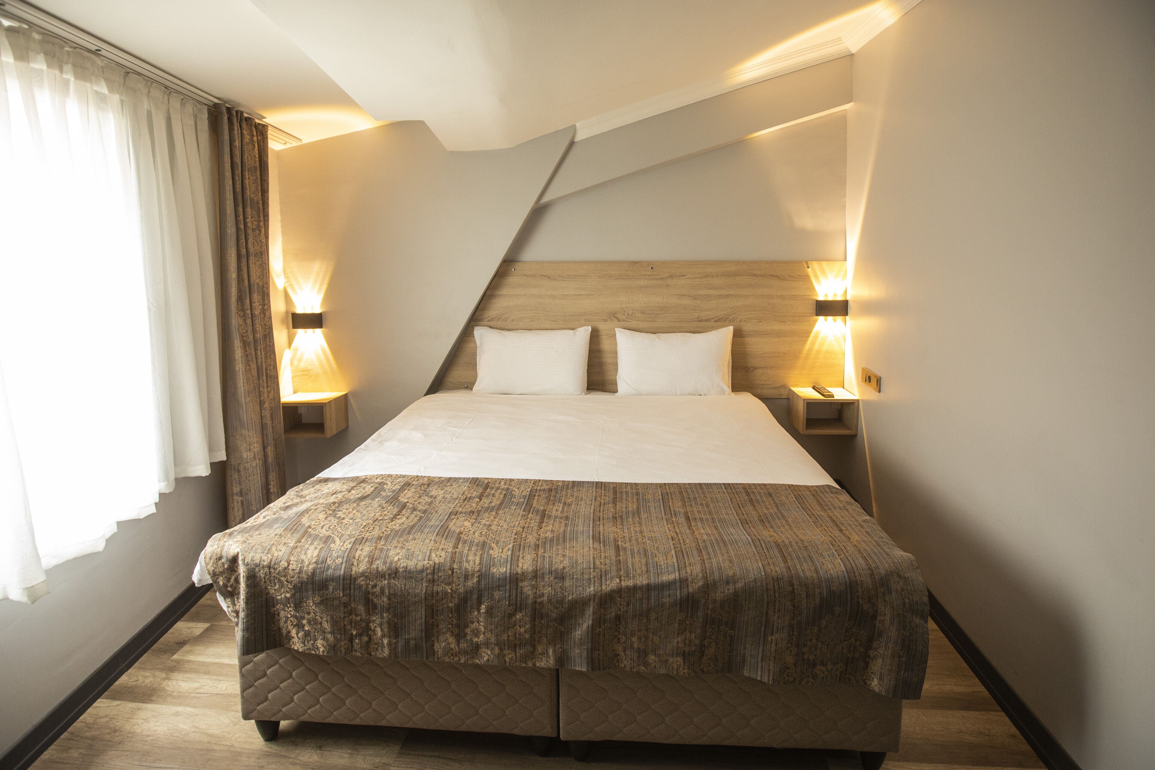 A neatly arranged hotel room with a large bed, two bedside tables, and a wooden headboard.