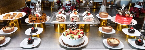 A variety of desserts on display, including cakes, pastries, and a chocolate dessert in a bowl.