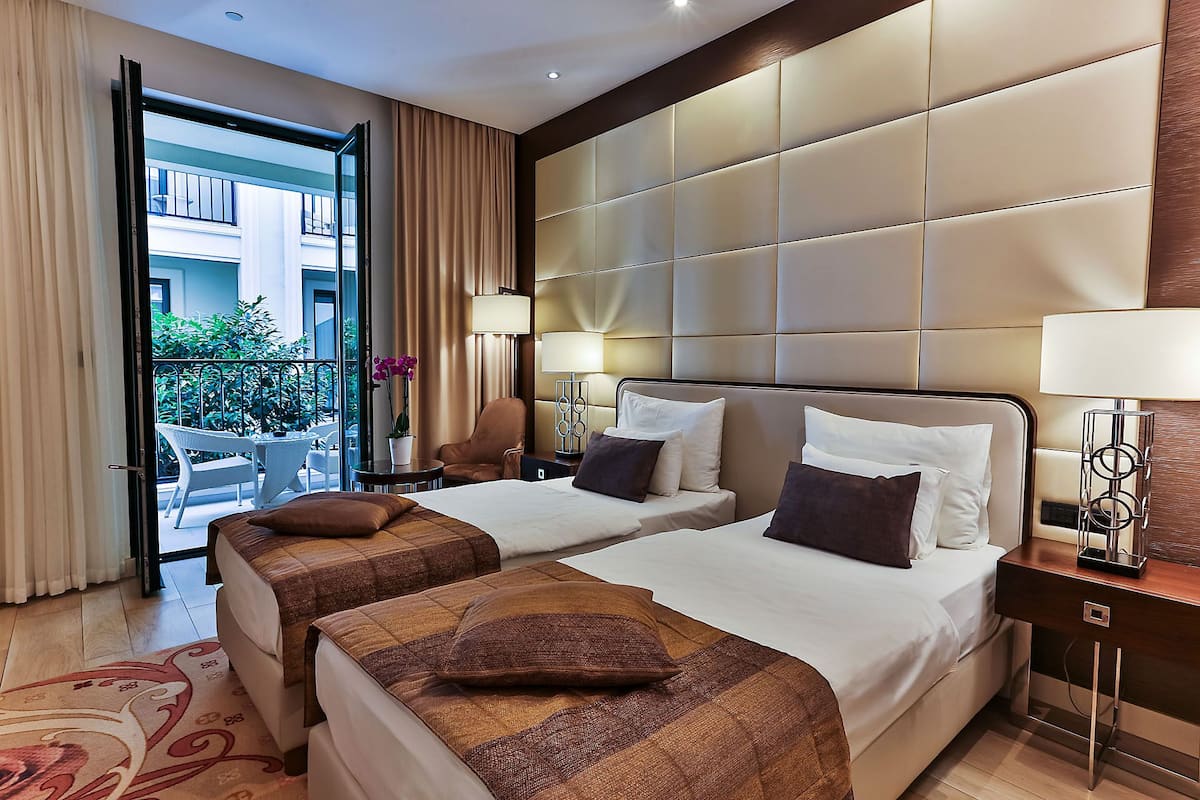 A hotel room with two beds, a balcony, and a view of the city.