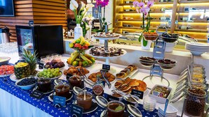 Ein Buffet mit verschiedenen Speisen und Getränken, darunter Obst, Gebäck und Soßen.