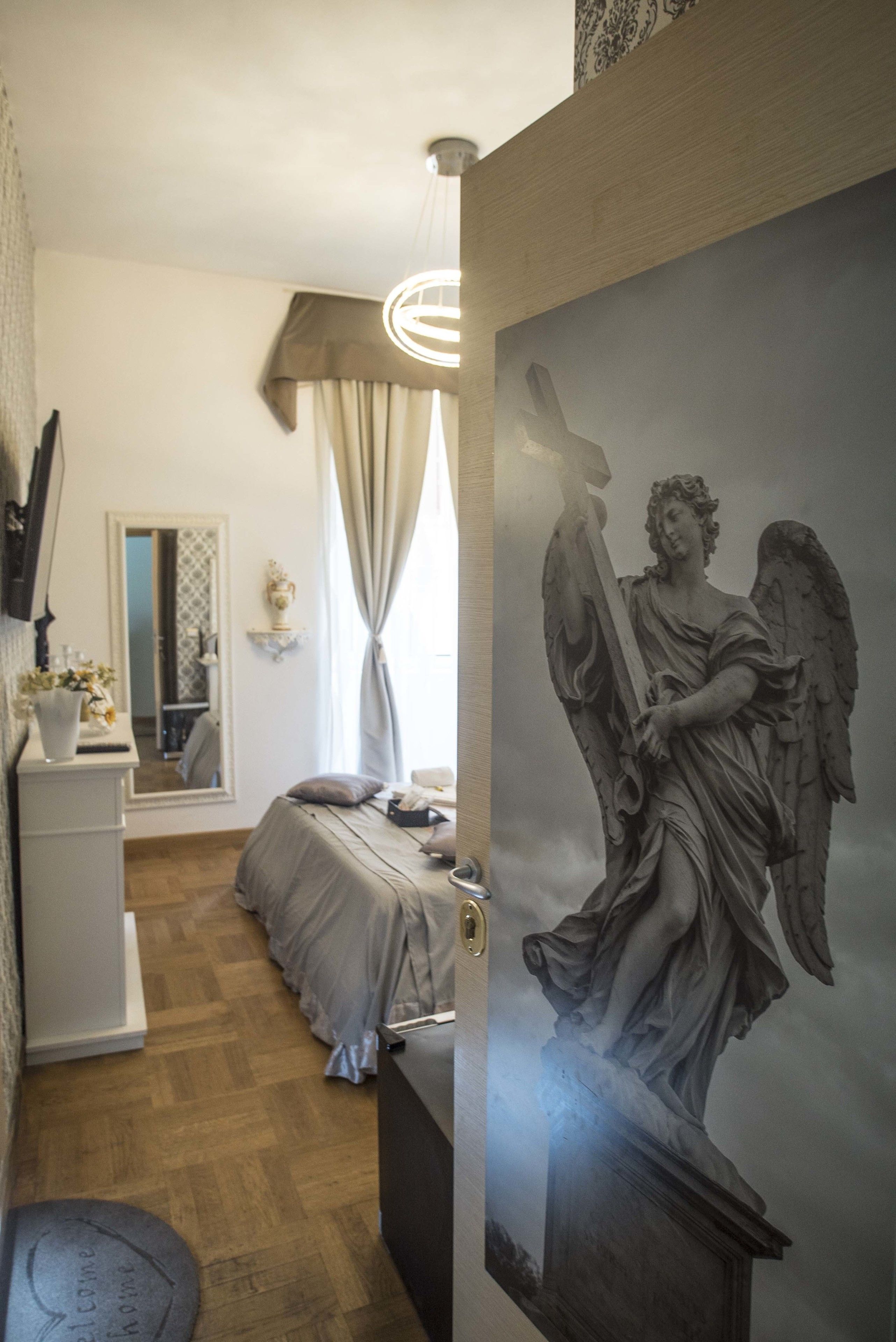 Un dormitorio con una cama, una mesita de noche, un espejo, un aparador y una escultura en la pared.