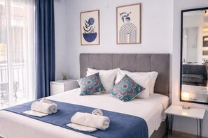 A hotel room with a bed, pillows, a bedside table, a mirror, and artwork on the wall. - AKMAN CITY HOTEL (Kusadasi)