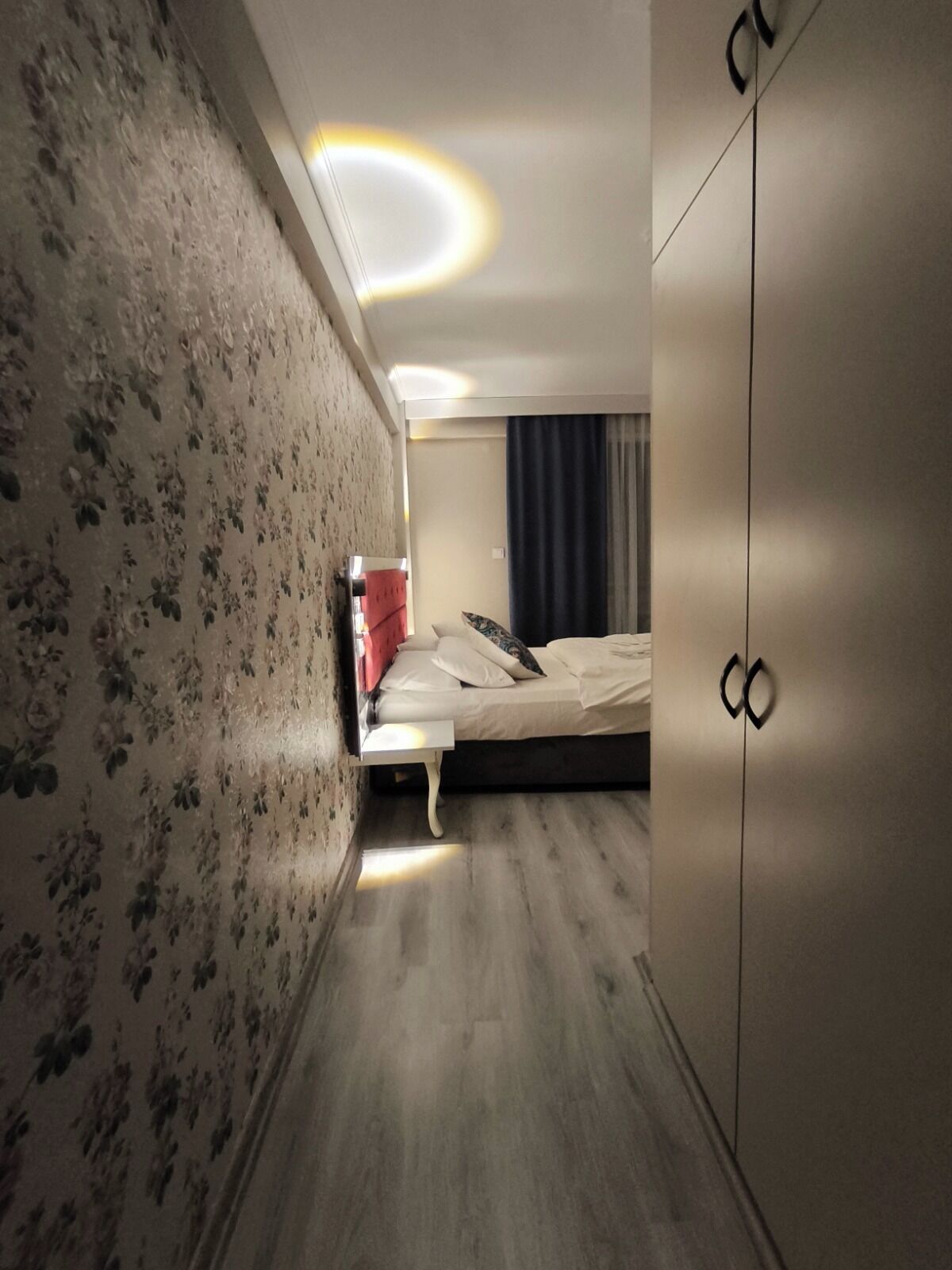A hotel room with a bed, a wardrobe, and a nightstand.