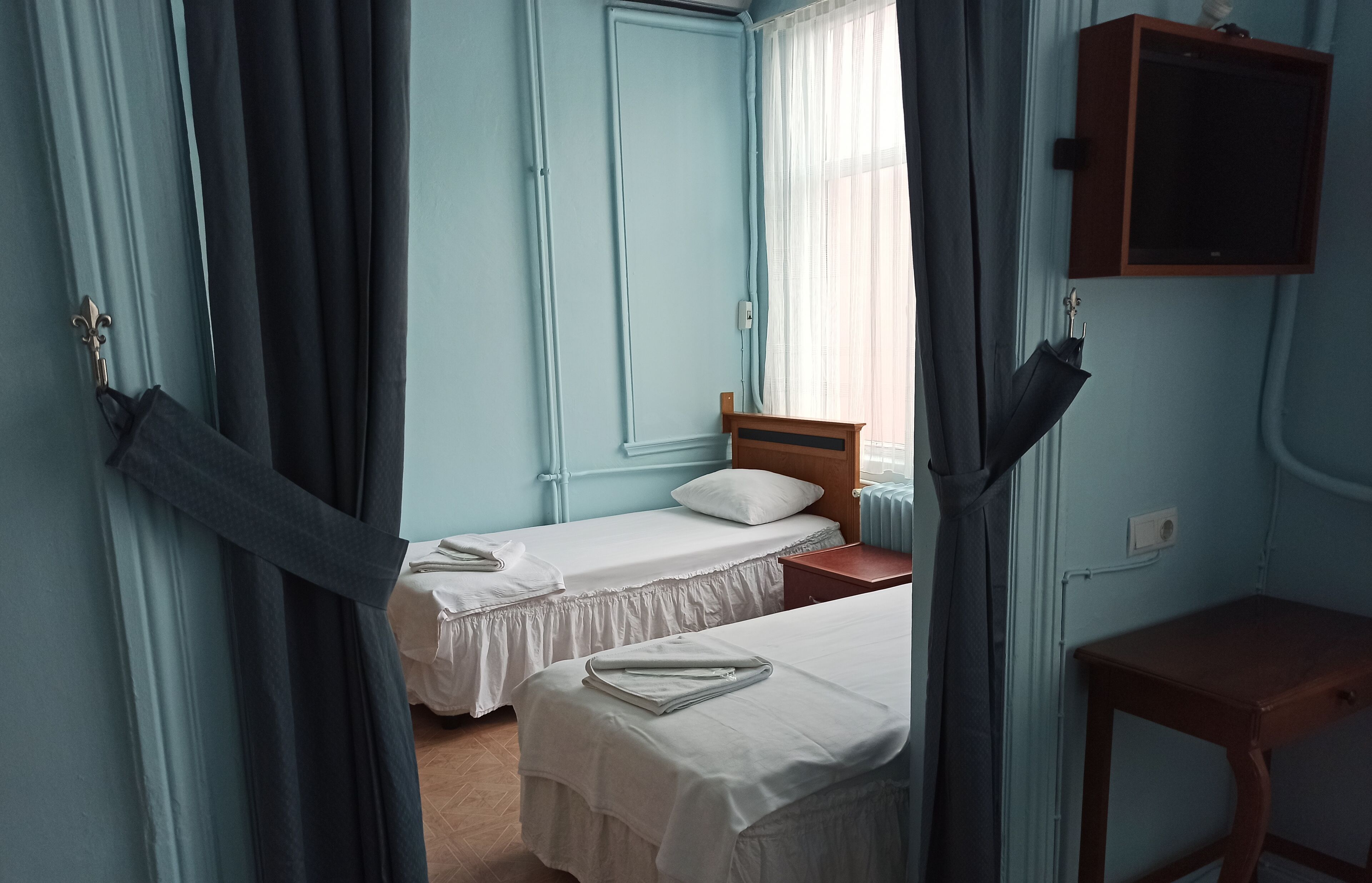 A room with two single beds, a wooden nightstand, a small table, and a cabinet.