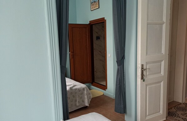 Un dormitorio con cama, puerta de madera y espejo.
