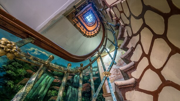A spiral staircase with a glass enclosure and a mural of a waterfall. - Yeni Hotel (Istanbul)