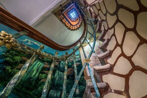 A spiral staircase with a glass enclosure and a mural of a waterfall. - Yeni Hotel (Istanbul)