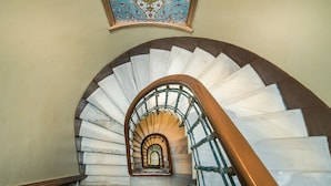 A spiral staircase with a wooden handrail and a decorative ceiling. - Yeni Hotel (Istanbul)