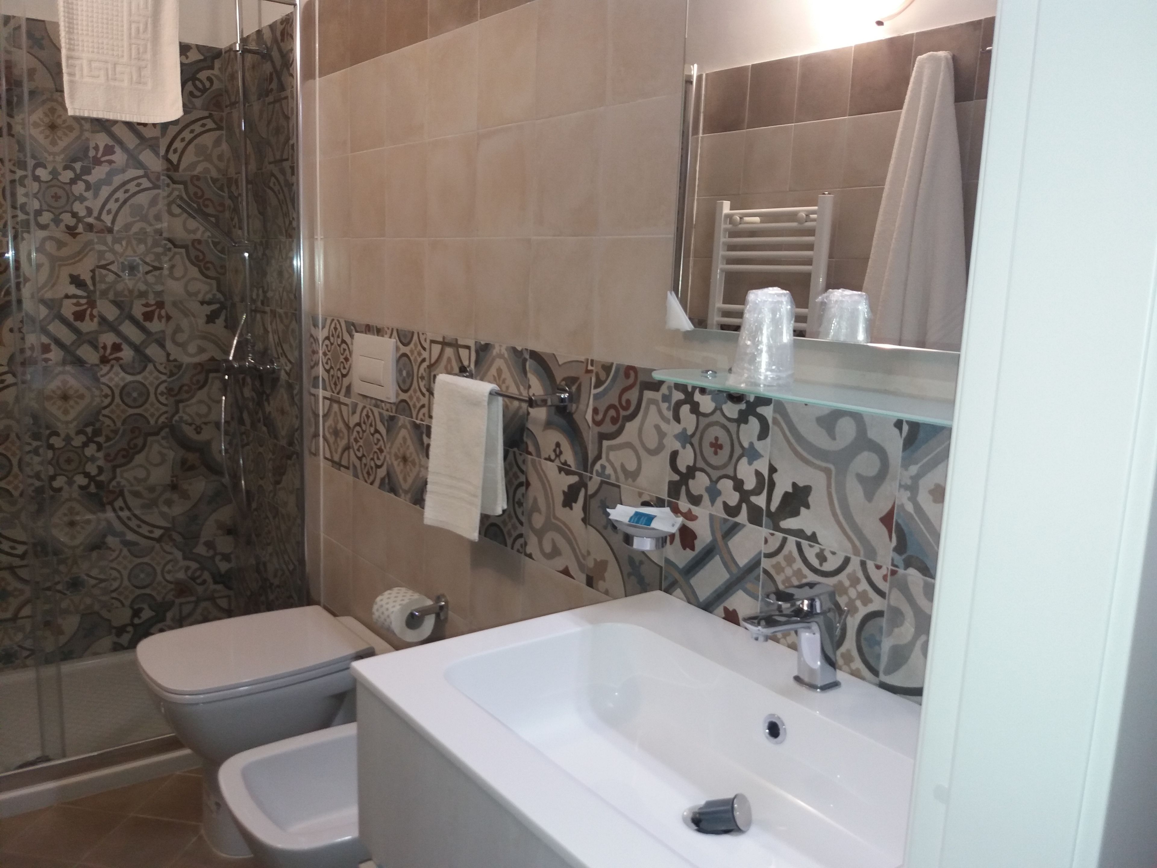 A bathroom with a shower, toilet, sink, and a mirror.