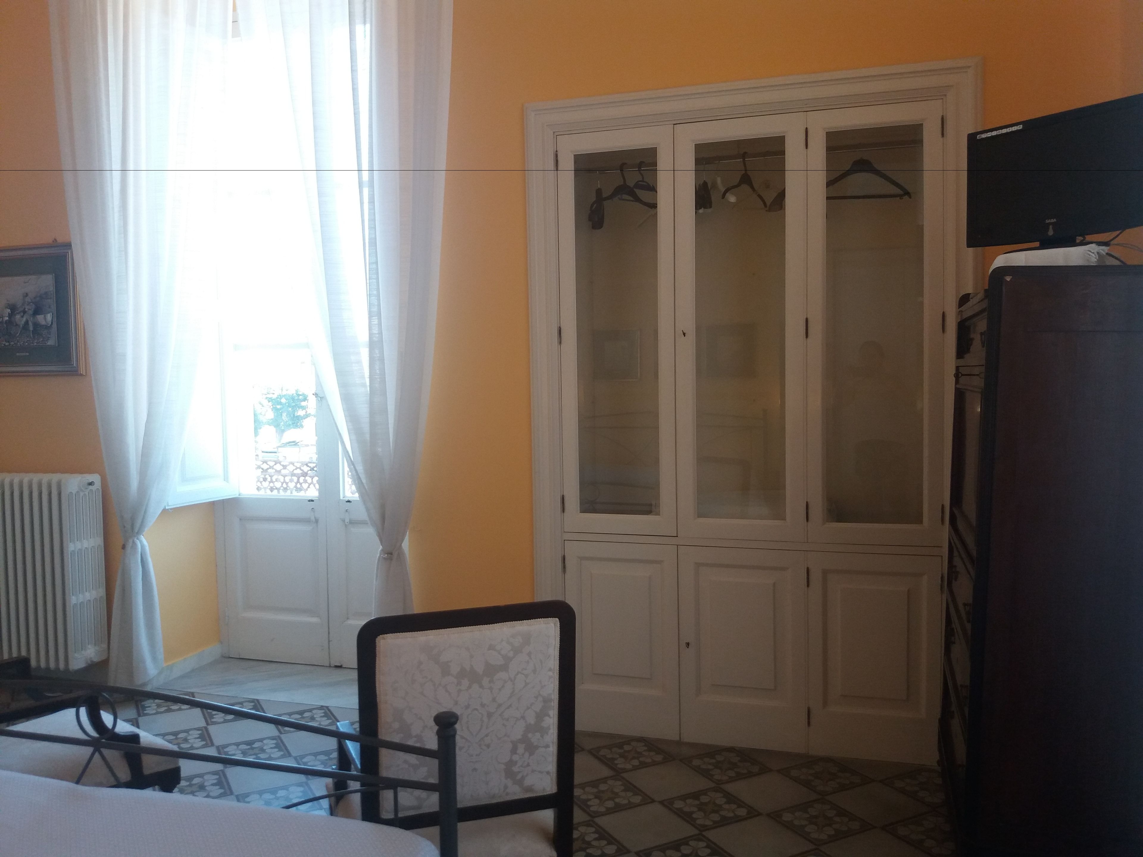 A room with a bed, a chair, a wardrobe, and a radiator.