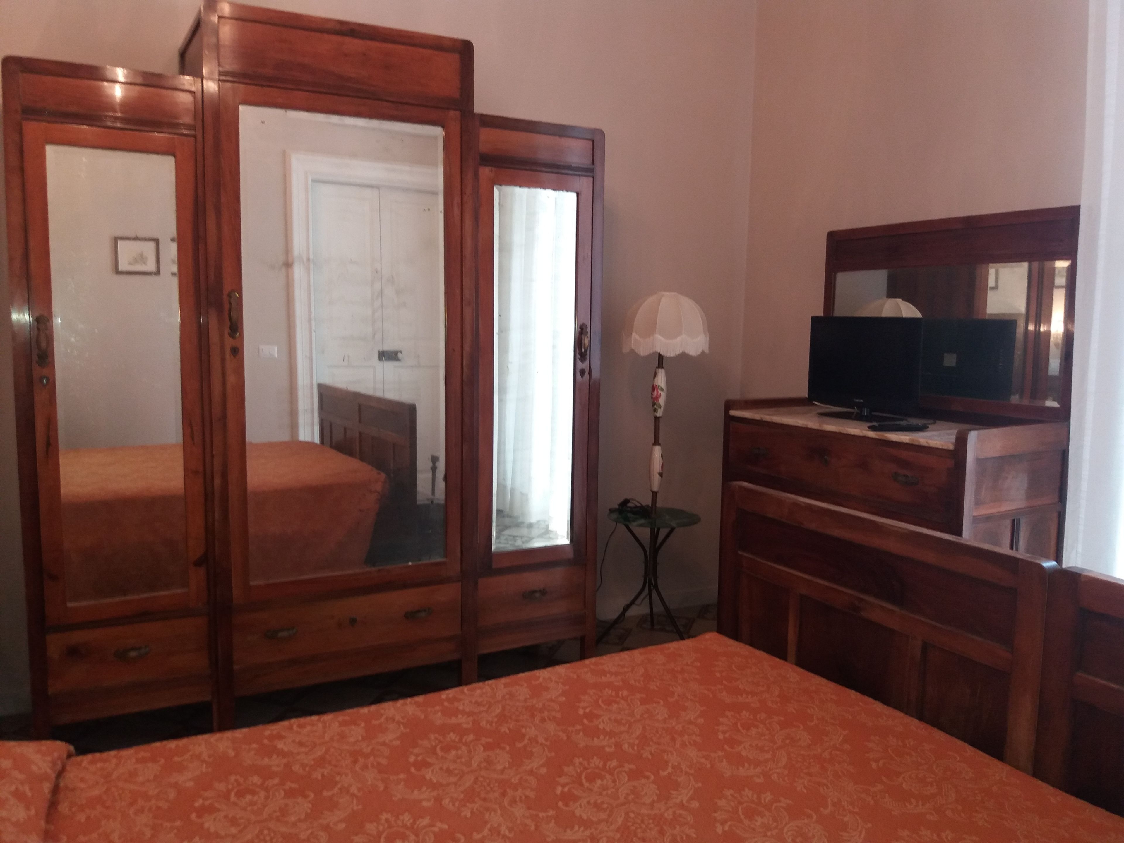 Ein Schlafzimmer mit einem Holzschrank, einem Fernseher auf einer Holzkommode und einer Lampe.