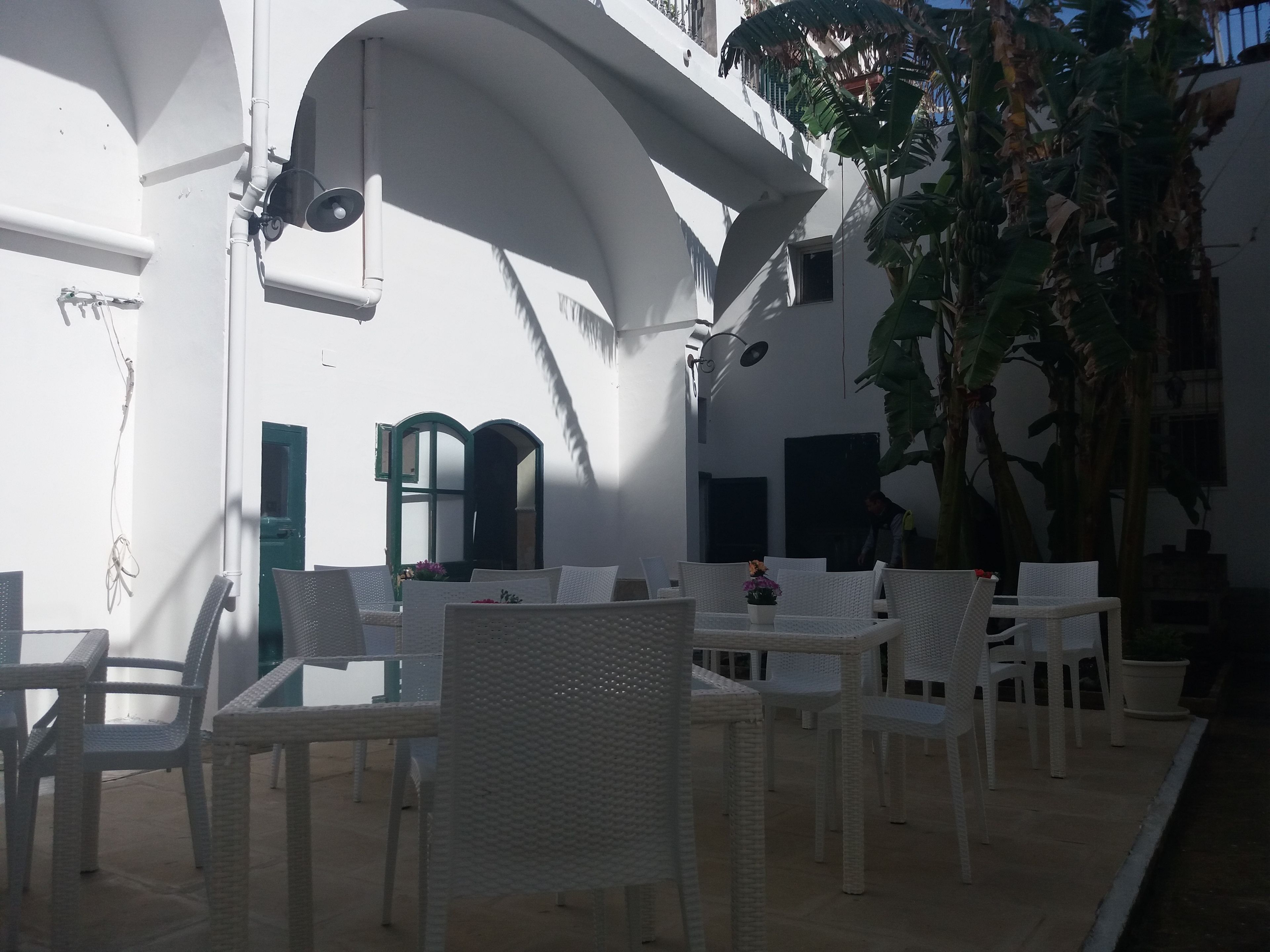 An outdoor seating area with white wicker furniture and a small table with flowers.