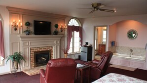 A room with a fireplace, leather chairs, a television, a ceiling fan, and a bathtub. - Smoketown Inn (Smoketown)