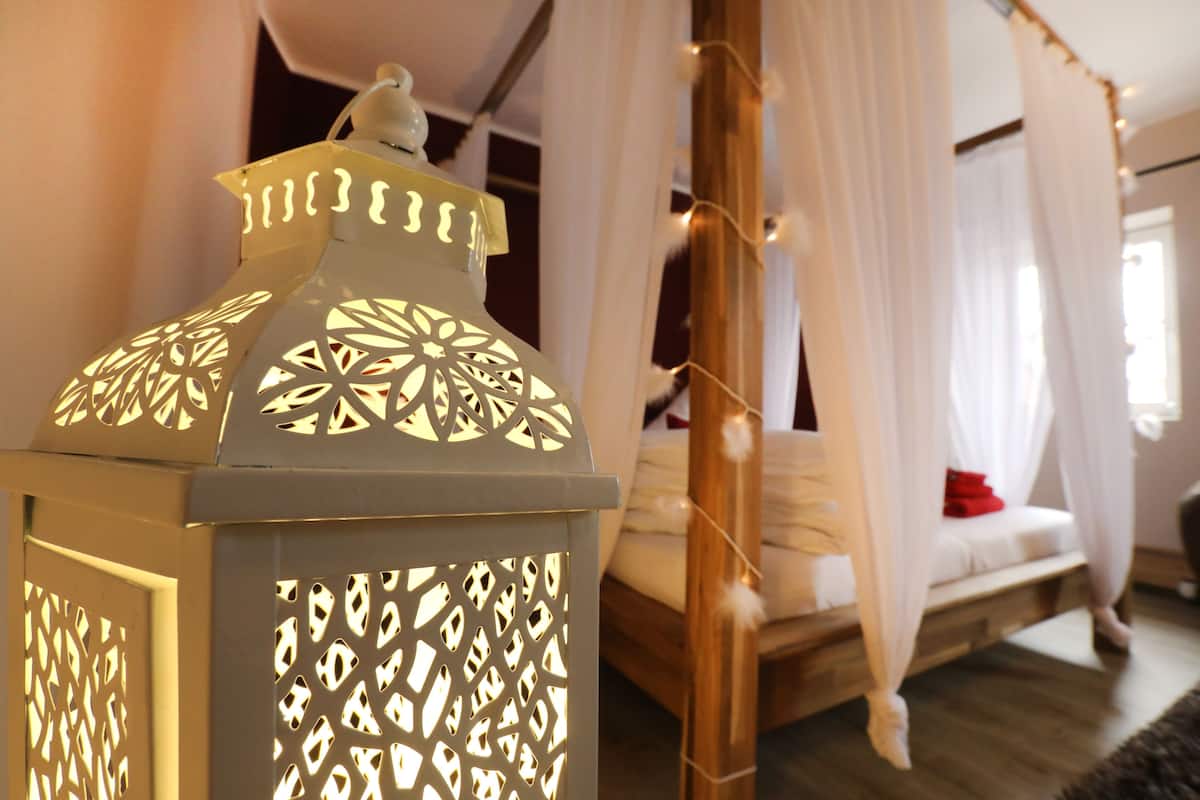 Ein Bett mit Baldachin, eine hängende Laterne und ein Holzboden.