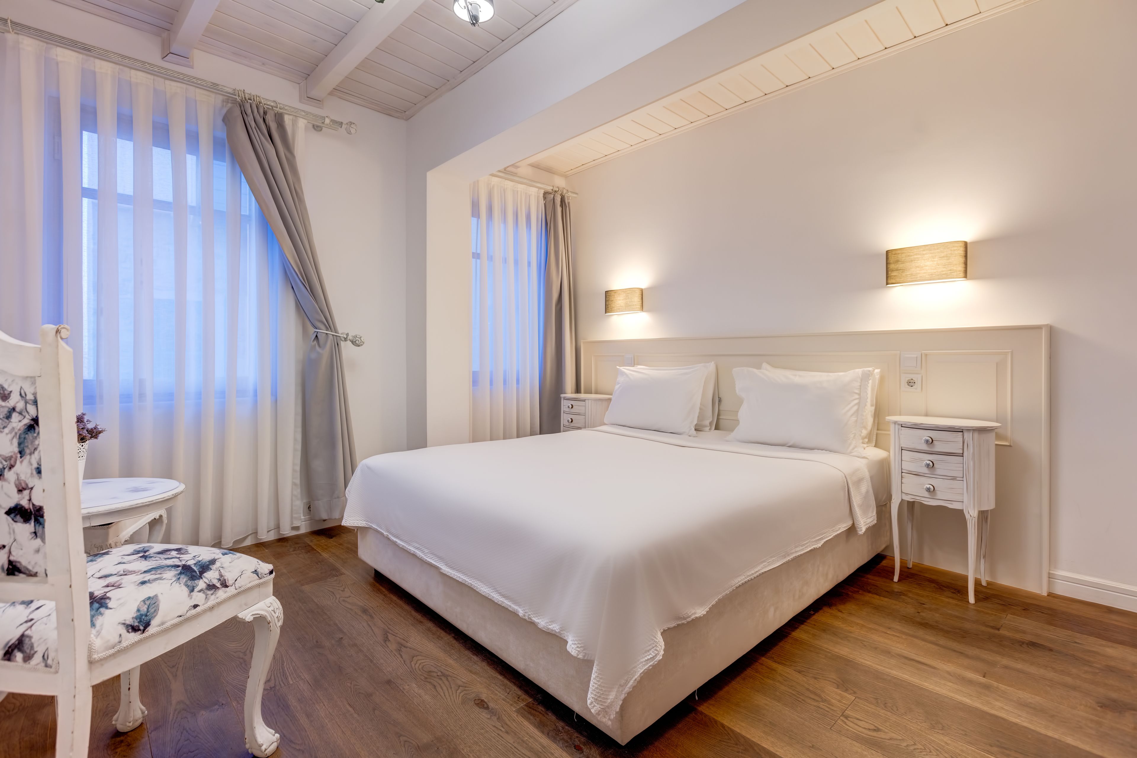 Une chambre bien rangée, avec un grand lit, des tables de chevet et une chaise.