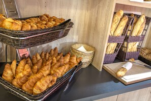 A display of various baked goods, including croissants and baguettes, arranged in wicker baskets on a countertop.