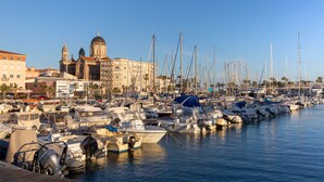 Un port de plaisance où sont amarrés de nombreux bateaux, une église imposante avec des coupoles, et une grande roue en arrière-plan.