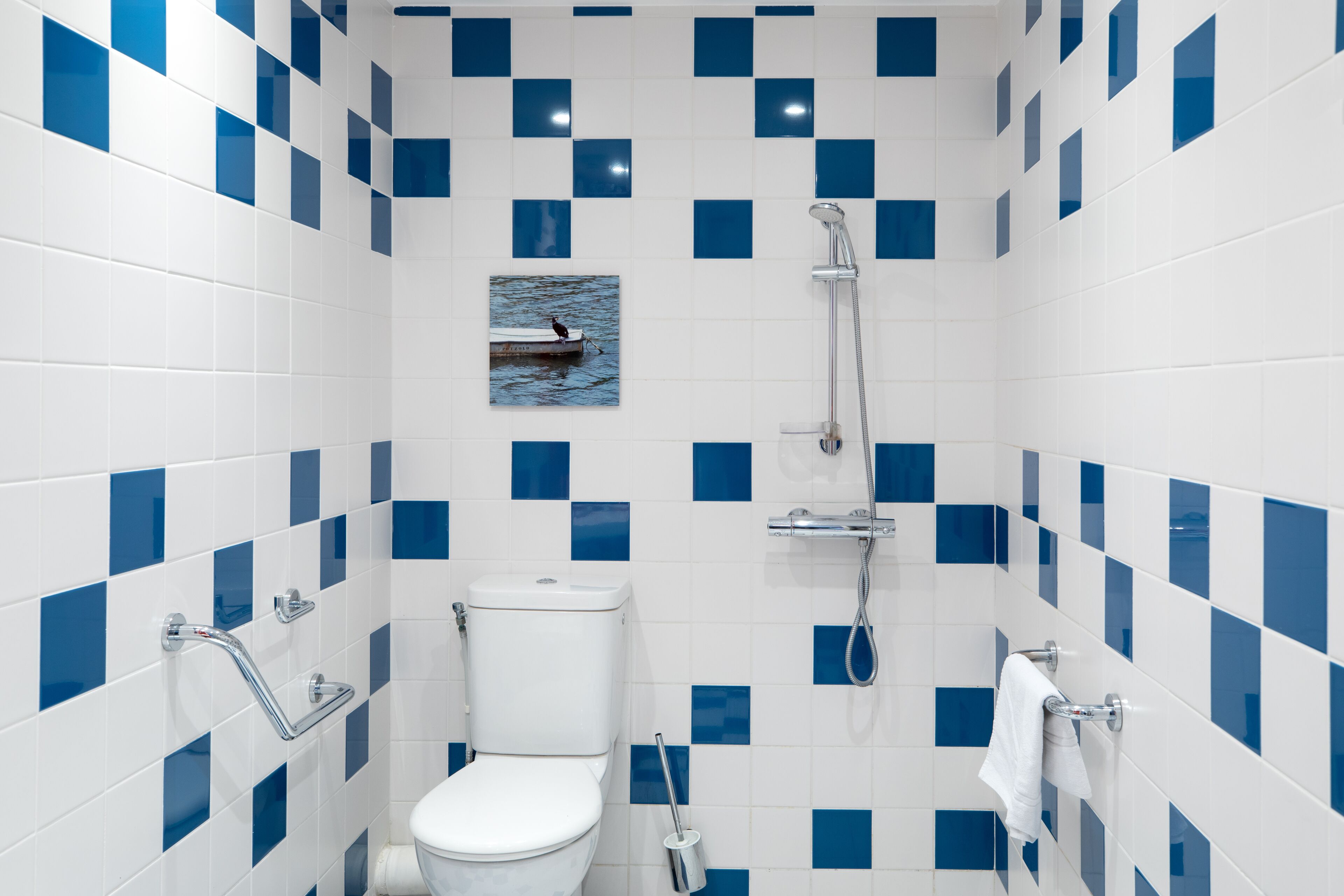 Une salle de bain avec des toilettes blanches, une douche et un porte-serviettes.