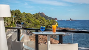 Une table avec des boissons, et une vue sur la mer et une montagne.