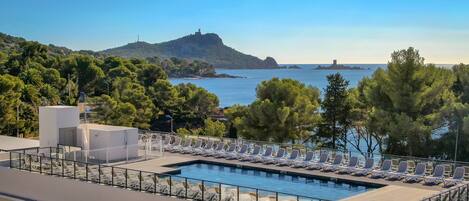 Een seizoensgebonden buitenzwembad en ligstoelen