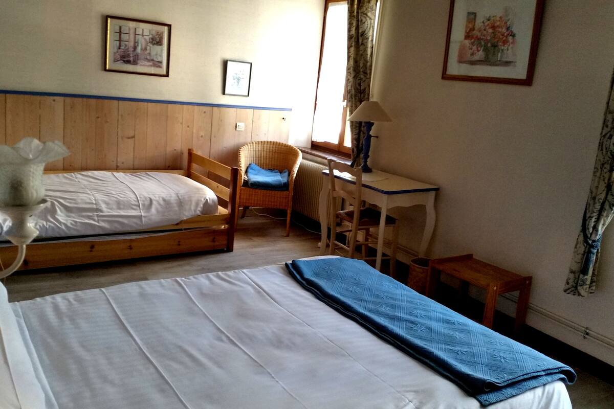 Ein Schlafzimmer mit zwei Einzelbetten, einem Sessel, einem Schreibtisch und einer Heizung.