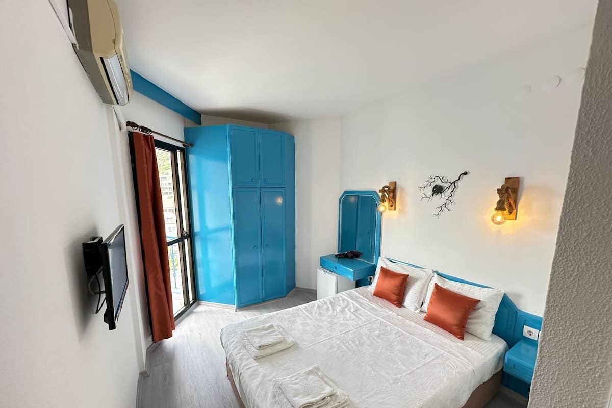 Habitación de hotel con cama, armario, escritorio y espejo.