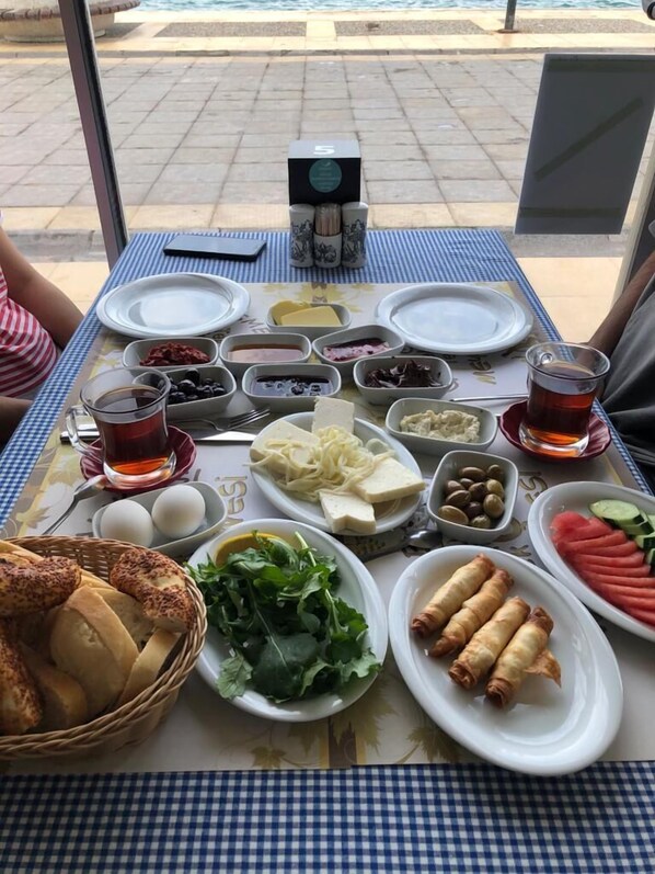 A table set with various dishes, including bread, eggs, and vegetables, indicating a meal setup. - Marin Hotel (Cesme)