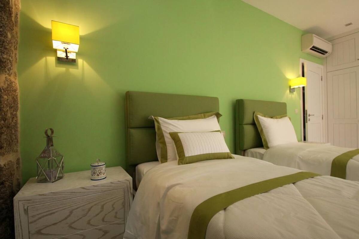 A hotel room with two beds, green walls, and a nightstand with decorative items.