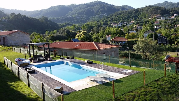 Une piscine dotée d’une terrasse en bois, entourée d’une pelouse et d’une clôture en bois.