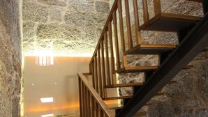 Un escalier en bois, avec des murs en pierre et un luminaire moderne au sommet.
