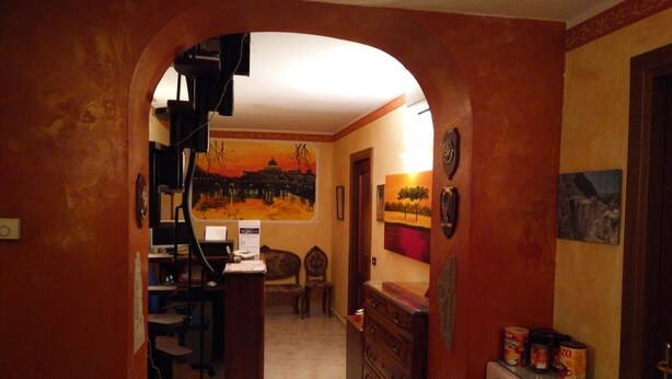 Un pasillo estrecho con un mural en la pared, un aparador de madera y un microondas sobre una mesita.
