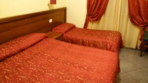 Una habitación de hotel con dos camas individuales, un cabecero de madera y cortinas rojas.