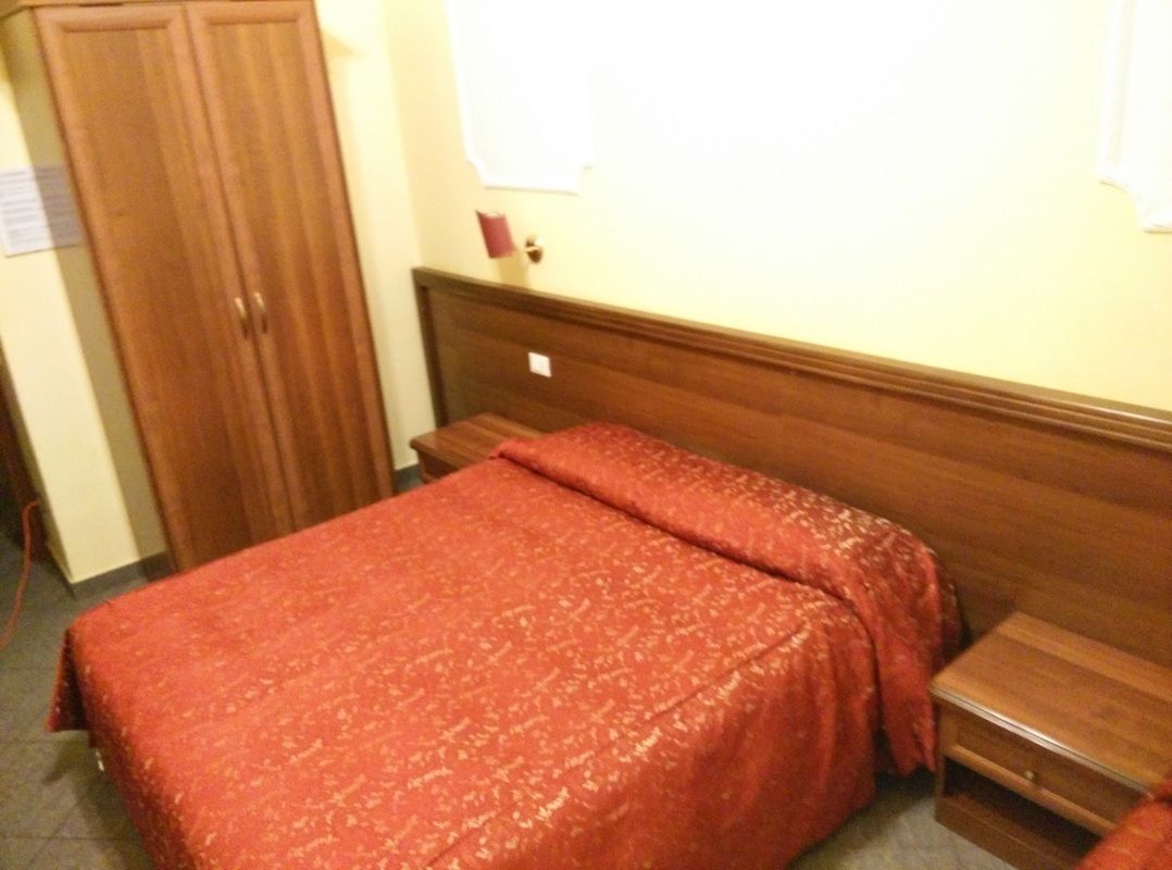 Ein Schlafzimmer mit einem hölzernen Bett, einem Schrank aus Holz und einem kleinen Nachttisch.
