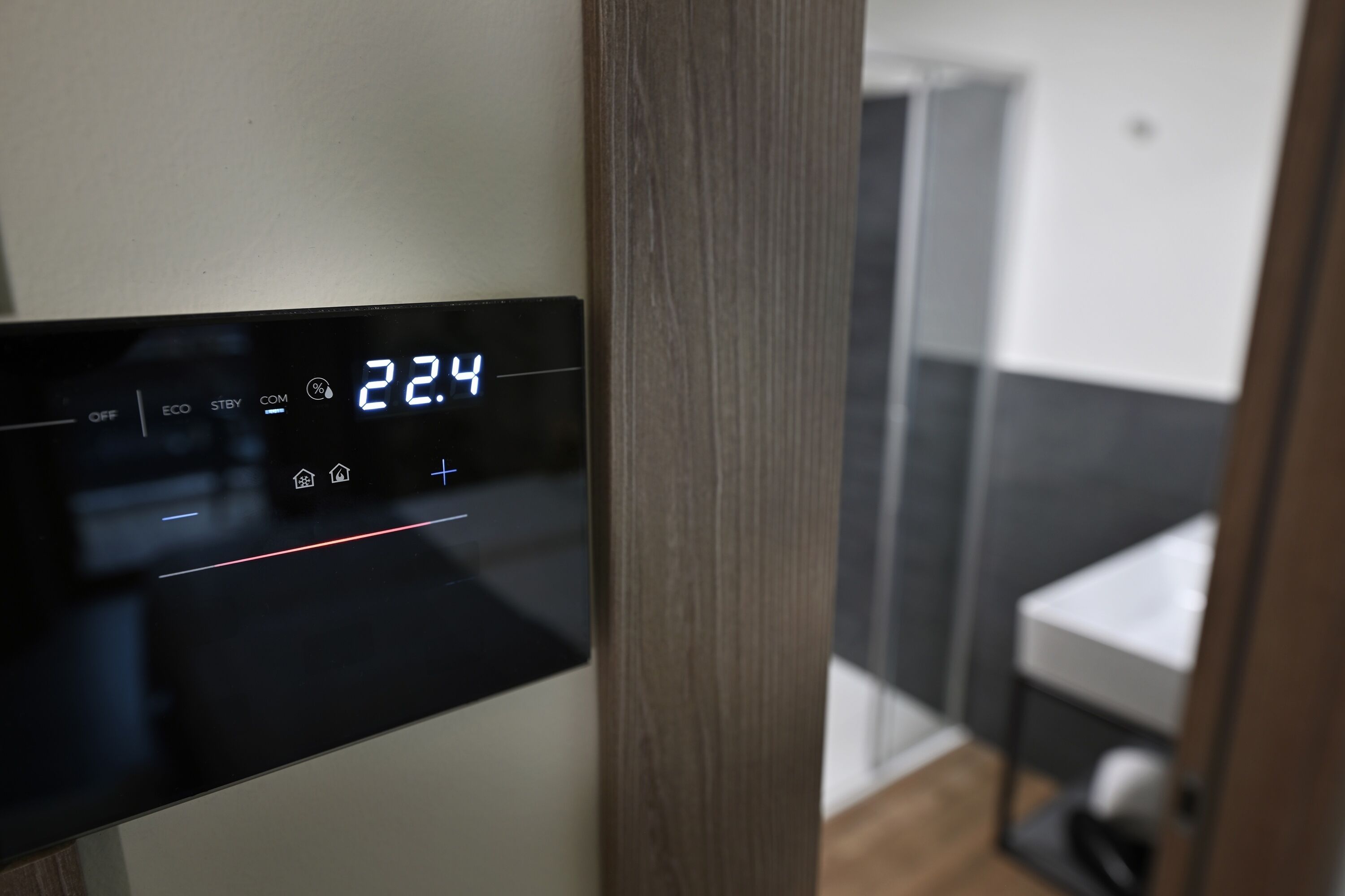 A digital display with the time 22:4, a control panel with various buttons, and a view of a bathroom with a shower and a toilet.